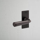 Digby Short Plate Fixed Door Handle Bronze Finish on White Background at an Angle