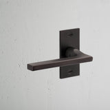 Clayton Short Plate Fixed Door Handle Bronze Finish on White Background at an Angle